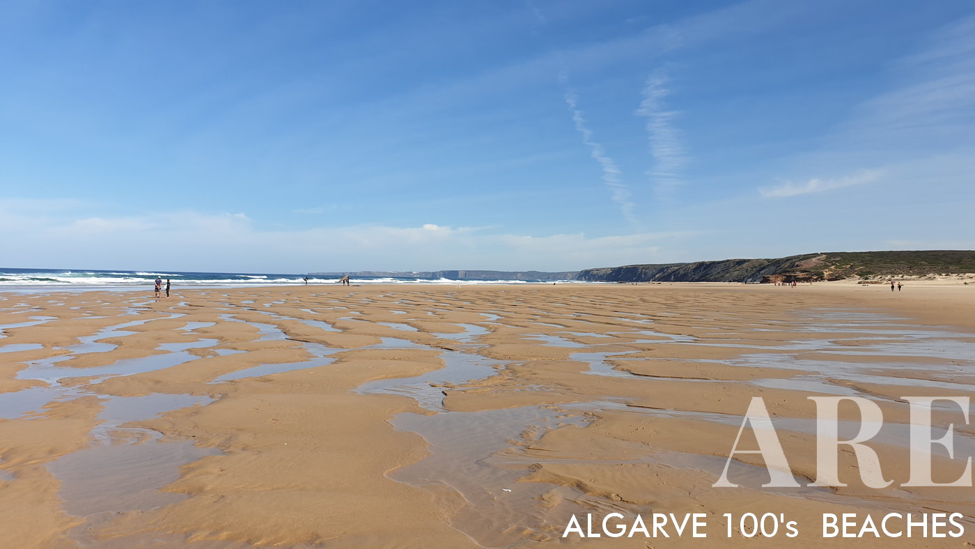La playa de Bordeira presenta un extenso arenal, acentuado por los bancos de arena que se descubren durante la marea baja. La playa está bordeada por acantilados exuberantes con vegetación verde.