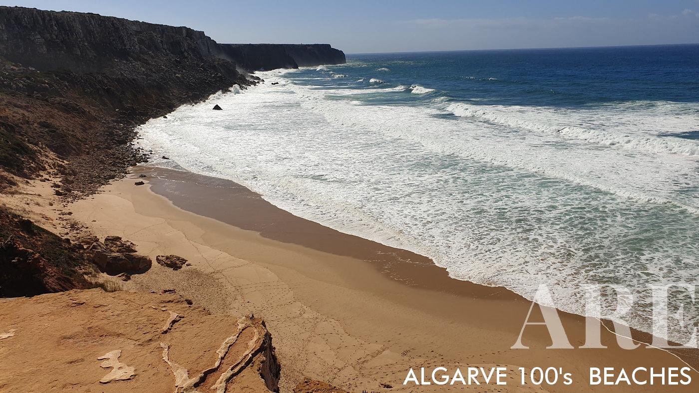 La playa de Telheiro está rodeada por acantilados de roca oscura que forman una barrera natural alrededor de la extensión de arena.